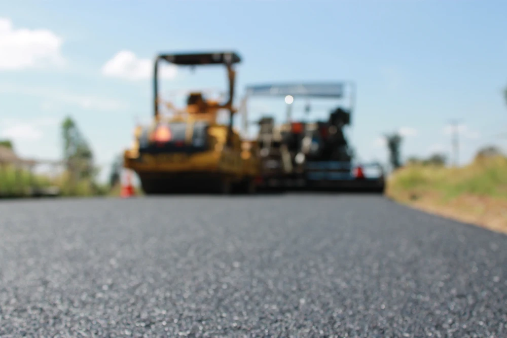 Chantier ext&eacute;rieur de peinture au sol, application de peinture rouge sur surface bitum&eacute;e