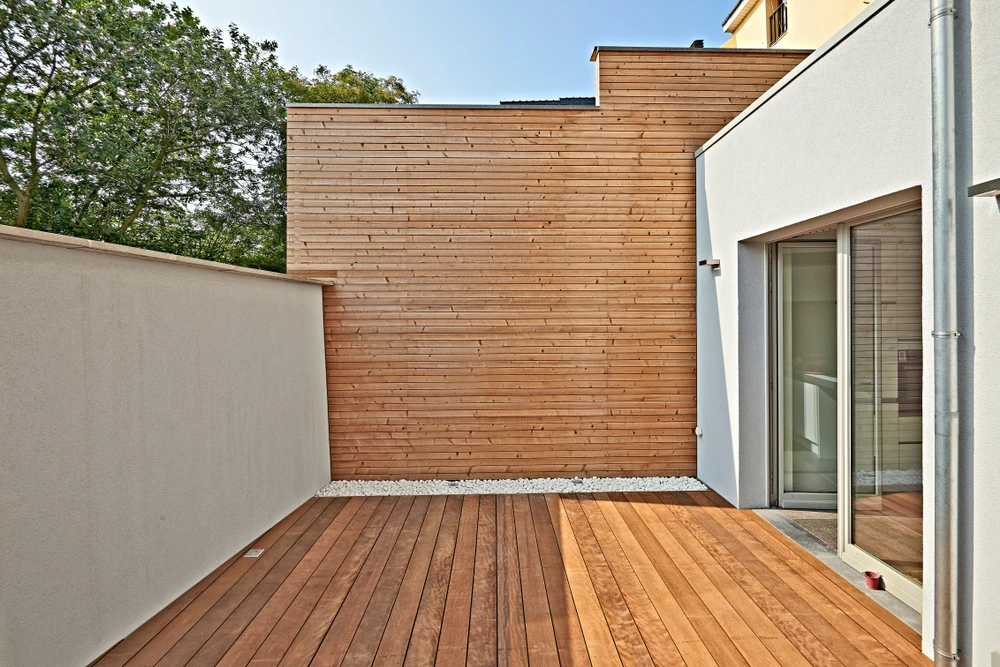 Terrasse extérieure moderne avec deck en bois exotique, mur de clôture en lames horizontales assorties