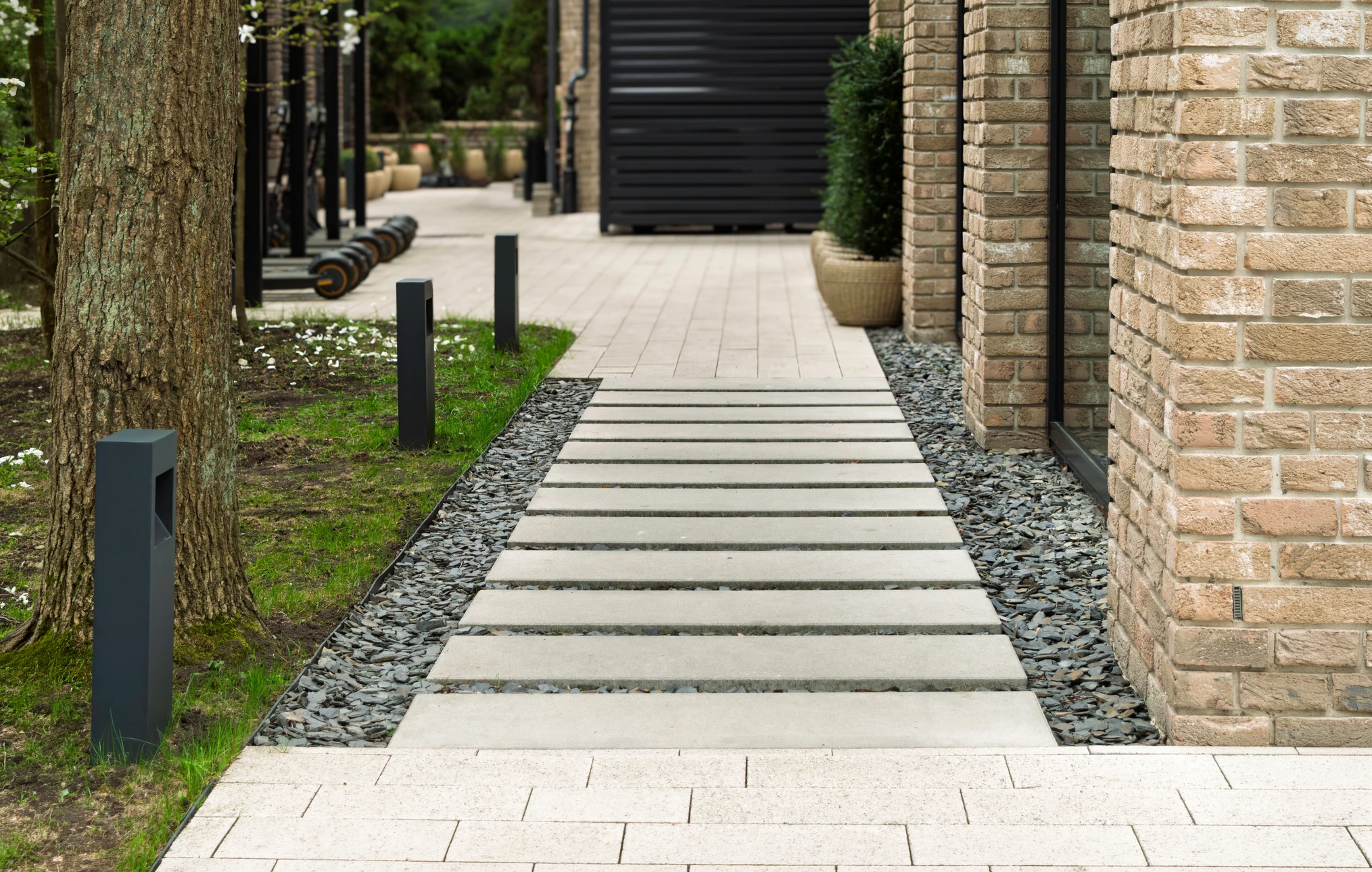 Jardin extérieur moderne avec terrasse surélevée en béton, mobilier contemporain et végétation dense